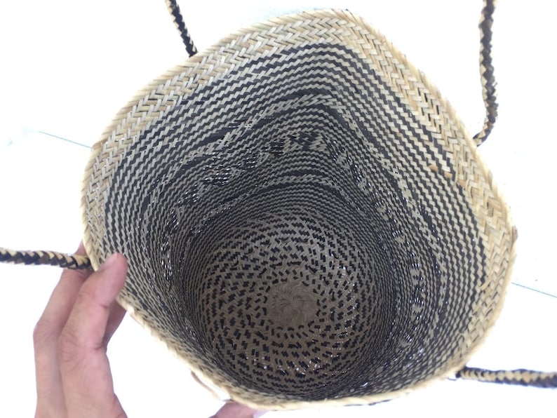 May include: A black and natural woven tote bag with two handles. The bag is made of a natural material and has a black and white pattern.