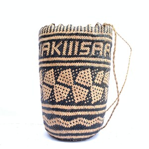 May include: A woven black and tan basket with a woven handle. The basket has a geometric pattern and the word "AKIISAR" woven into the side.