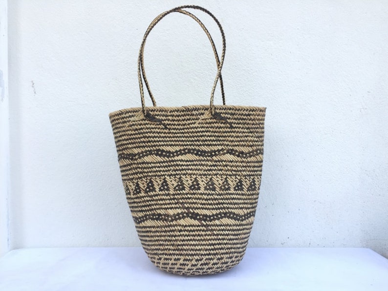 May include: A large, woven tote bag with black and brown geometric patterns. The bag has two thick, woven handles.
