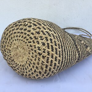 May include: A large, woven tote bag with a black and natural straw pattern. The bag is made of natural materials and has a woven handle.