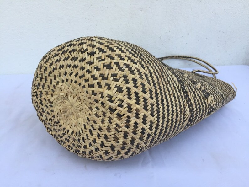 May include: A large, woven tote bag with a black and natural straw pattern. The bag is made of natural materials and has a woven handle.