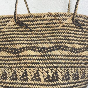 May include: A large, woven tote bag with black and natural brown stripes. The bag has two thick, woven handles.