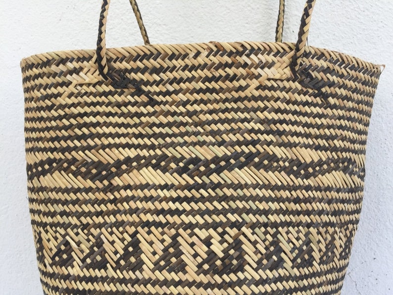 May include: A large, woven tote bag with black and natural brown stripes. The bag has two thick, woven handles.
