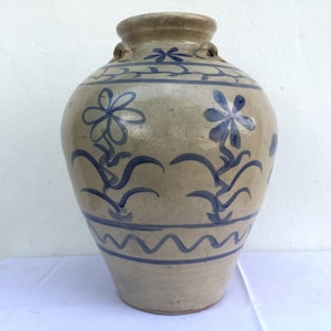Op de afbeelding: Een grote, grijze keramische pot met blauwe bloemen- en golfmotieven. De pot heeft twee kleine handvatten aan de bovenkant.