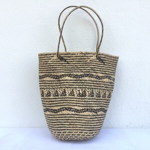 May include: A large, woven tote bag with black and brown geometric patterns. The bag has two long handles.