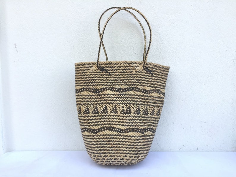 May include: A large, woven tote bag with black and brown geometric patterns. The bag has two long handles.