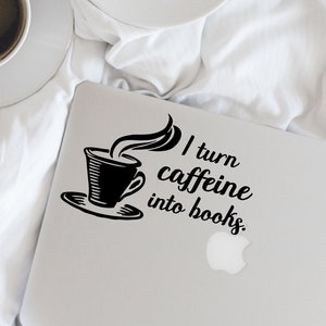 May include: A white laptop with a black sticker that says "I turn caffeine into books." The sticker features a stylized image of a coffee cup with steam rising from it.