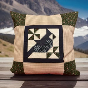 Peut inclure: Coussin carré décoratif avec un motif patchwork. Le coussin présente un carré central avec un motif d'oiseau bleu marine et blanc, entouré d'une bordure marine. Les coins ont un motif floral et le centre un motif à carreaux beige et blanc.