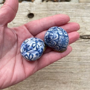 Può includere: Due piccoli ornamenti rotondi in ceramica con un design a motivi blu e bianchi. Gli ornamenti sono decorati con intricati motivi floreali.