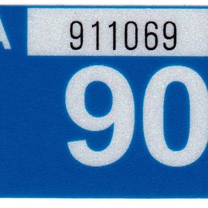 May include: A blue sticker with a white background and the number 90 in large white font. The sticker also has a smaller white rectangle with the letter A and the number 911069 in black font.