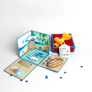 May include: A blue and red explosion box with a beach scene on the inside. The box is open to reveal a beach scene with a beach chair, umbrella, and palm trees. The box also has a tag that says "Open for a Surprise!" and a sign that says "Surprise! We're going to Turks & Caicos!"