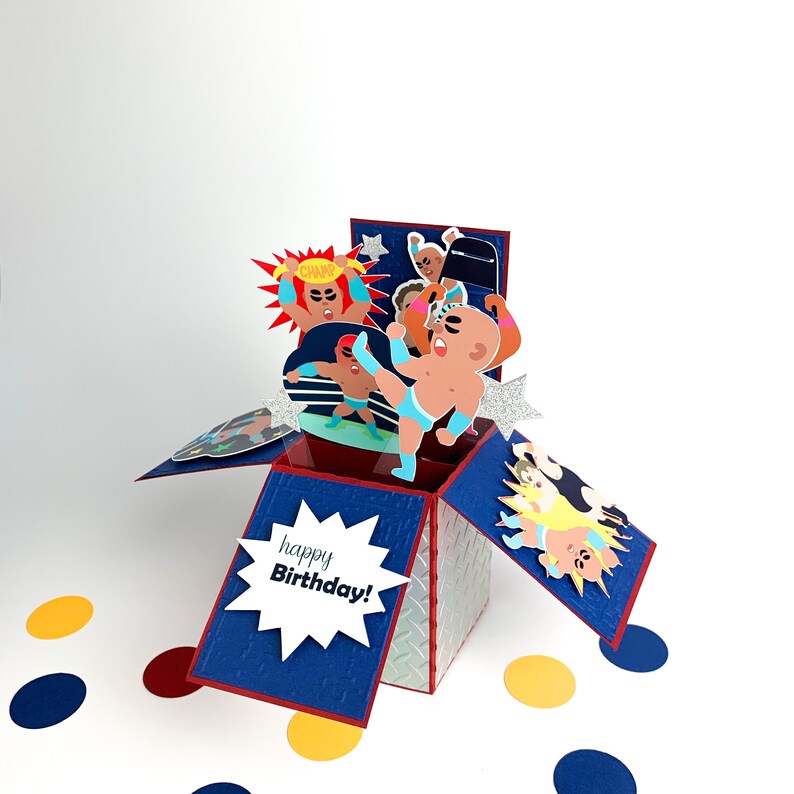 Puede incluir: Una tarjeta emergente azul y roja con tem&aacute;tica de lucha libre. La tarjeta presenta a un luchador con un cintur&oacute;n de campeonato y las palabras "&iexcl;Feliz cumplea&ntilde;os!" en el frente.