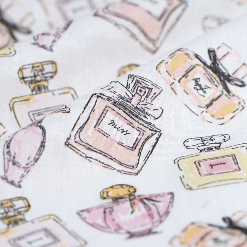 May include: White fabric with a repeating pattern of pink, yellow, and black perfume bottles. The bottles are drawn in a whimsical style with some text on the labels.