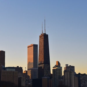 May include: A view of the Chicago skyline at sunset, with the Willis Tower, formerly known as the Sears Tower, standing tall in the center.