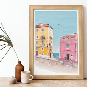 May include: A watercolor painting of two buildings, one yellow and one pink, with a blue sky and sea in the background.