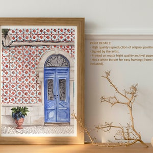 Puede incluir: Pintura acuarela de una puerta azul con una reja de hierro decorativa. La puerta est&aacute; ubicada en un edificio con azulejos de patrones rojos y blancos. La pintura est&aacute; enmarcada en un marco de madera claro.
