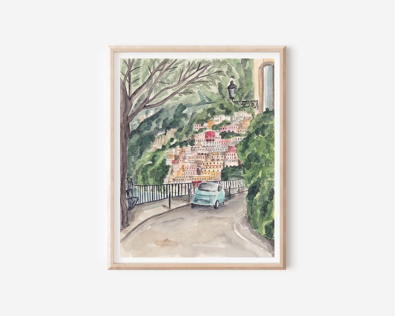 May include: A watercolour painting of a blue car driving on a winding road in a colourful Italian village. The road is lined with lush green trees and a stone wall. The village is built on a hillside and has many colourful buildings.