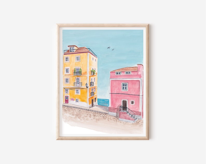 May include: Watercolor painting of two buildings, one yellow and one pink, with a blue sky and sea in the background.