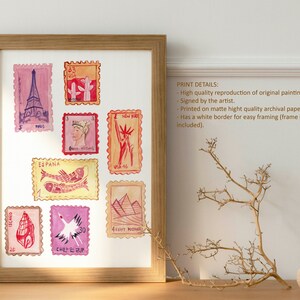 May include: Watercolor print of postage stamps featuring landmarks and cultural symbols. The stamps include images of the Eiffel Tower, cacti, the Statue of Liberty, and pyramids. The print is framed in a light brown wooden frame.