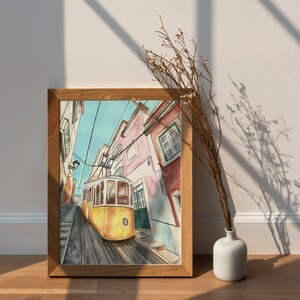 May include: A watercolor painting of a yellow tram traveling up a hill in Lisbon, Portugal. The tram is surrounded by colorful buildings with red tile roofs.