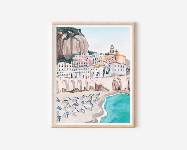 May include: Watercolor painting of a coastal town with colorful buildings, a stone bridge, and a beach with blue and white striped umbrellas.