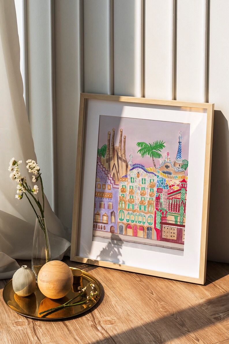 May include: A framed watercolor painting of colorful buildings with a palm tree in the foreground. The buildings are in a style reminiscent of Barcelona, Spain.