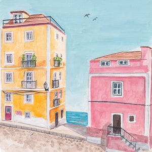 May include: Watercolor painting of two buildings on a cobblestone street. The building on the left is yellow with a red door and multiple windows. The building on the right is pink with a brown door and a staircase. The buildings are near a blue body of water.