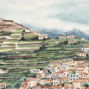 May include: Watercolor painting of a hillside village with terraced fields. The village is made up of white buildings with orange roofs. The hillside is green and brown with a blue sky in the background.