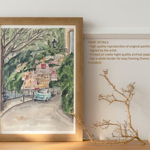 May include: Watercolour painting of a blue car driving up a winding road in a colourful Italian village. The road is lined with trees and the village is built into the hillside. The painting has a white border.