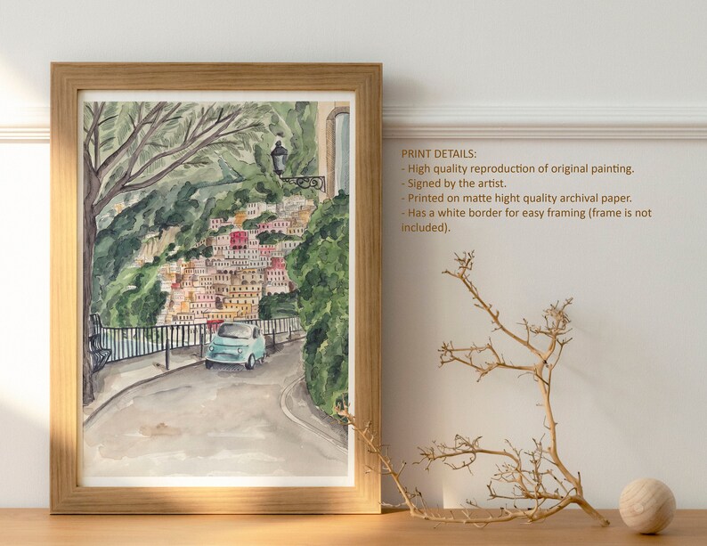 May include: Watercolour painting of a blue car driving up a winding road in a colourful Italian village. The road is lined with trees and the village is built into the hillside. The painting has a white border.