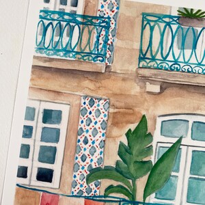 May include: Watercolour painting of a building with a balcony and a plant. The building is painted in shades of brown and beige, with blue tiled accents. The balcony has a blue railing and a plant in a terracotta pot. The painting is done in a realistic style.