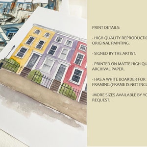 May include: Watercolor painting of a row of colorful houses with white trim and black windows. The houses are painted in shades of yellow, purple, and red. The painting is signed by the artist and printed on archival paper.