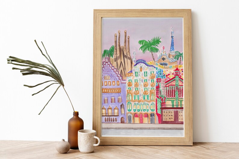May include: A framed illustration of colorful buildings in Barcelona, Spain. The buildings are painted in a whimsical style with bright colors and geometric patterns. The illustration includes a palm tree and a blue sky.