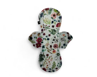 May include: A white reusable cloth menstrual pad with a floral print featuring red, pink, and blue flowers, green leaves, and brown mushrooms.