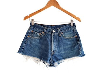May include: A pair of blue denim shorts with frayed edges. The shorts have a classic five-pocket design and a button fly.