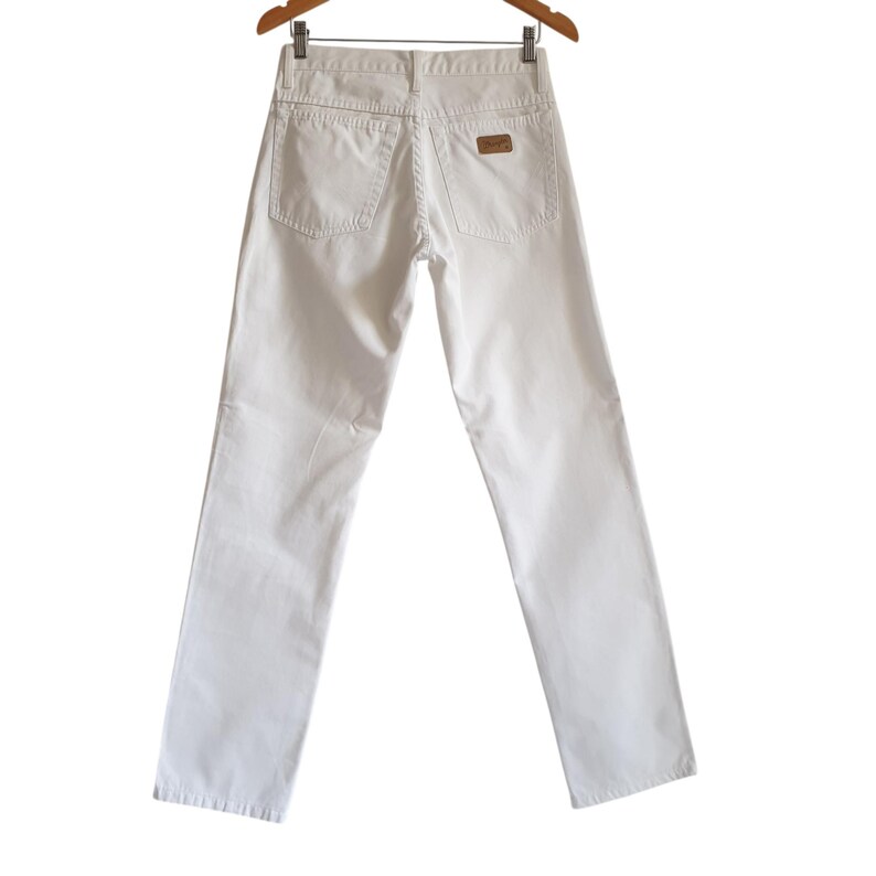 May include: A pair of white denim pants hanging on a wooden hanger. The pants have a classic five-pocket design with a small brown patch on the back pocket. The pants are a solid, bright white color.