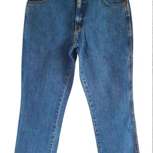 May include: A pair of blue denim jeans with a straight leg fit. The jeans have a classic five-pocket design and a button fly.