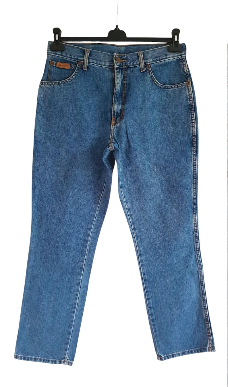 May include: A pair of blue denim jeans with a straight leg fit. The jeans have a classic five-pocket design and a button fly.