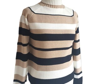 May include: A striped turtleneck sweater with black, white, and beige stripes. The sweater is long-sleeved and has a ribbed collar.