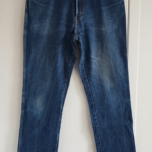 May include: A pair of blue denim jeans with a brown leather patch that says "Wrangler" on the back waistband.