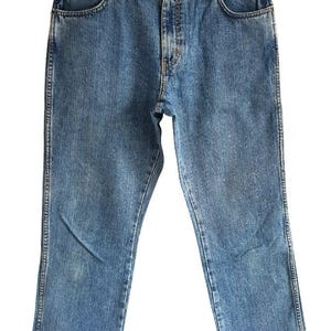 May include: Light blue denim jeans with a classic five-pocket design. The jeans are hanging on a black hanger against a white background. The jeans have a straight leg cut and a button and zipper closure.
