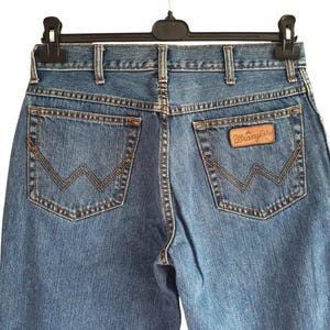 May include: A pair of blue denim jeans with a brown leather patch that says "Wrangler" on the back pocket.
