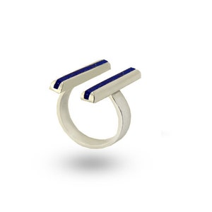 May include: A silver ring with two parallel blue lapis lazuli bars.