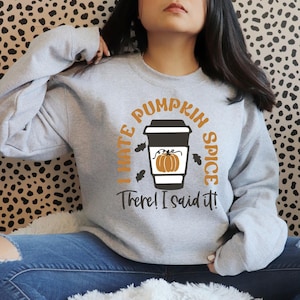 May include: A grey sweatshirt with the text "I hate pumpkin spice. There! I said it!" in black and orange. A stylised orange pumpkin is inside a coffee cup.