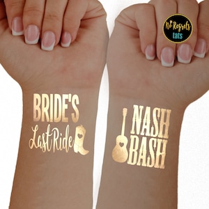 Puede incluir: Dos tatuajes temporales dorados en las mu&ntilde;ecas de una persona. El tatuaje de la mu&ntilde;eca izquierda dice "Bride's Last Ride" con una bota y un coraz&oacute;n. El tatuaje de la mu&ntilde;eca derecha dice "I Nash Bash" con una guitarra.
