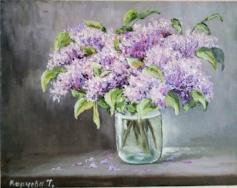 May include: An oil painting depicting a bunch of purple lilacs in a clear glass jar. The flowers are in full bloom with green leaves. The background is a muted grey, and the artist's signature is in the bottom left corner.