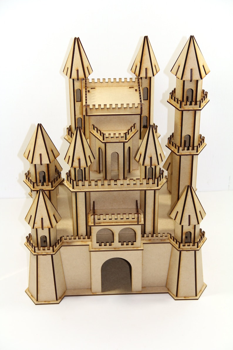 May include: A wooden model of a castle with multiple towers and a large arched entrance. The castle is made of light brown wood and has brown details.