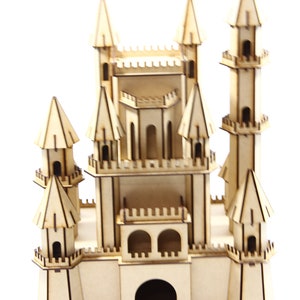 May include: A wooden model of a castle with multiple towers and a large arched entrance. The castle is made of light brown wood and has a detailed design.