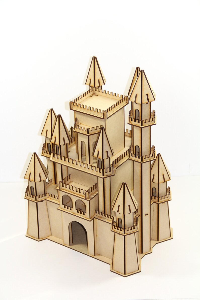 May include: A wooden model of a castle with multiple towers and a large arched entrance. The castle is made of light brown wood and has intricate details.