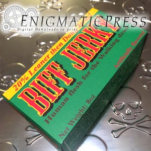 Op de afbeelding: Een groene, gele en rode doos met de tekst "Biff Jerky" in grote rode letters. De doos heeft de tekst "20% Leaner then Dough", "Human flesh for the Walking dead" en "Net Weight: 8oz".